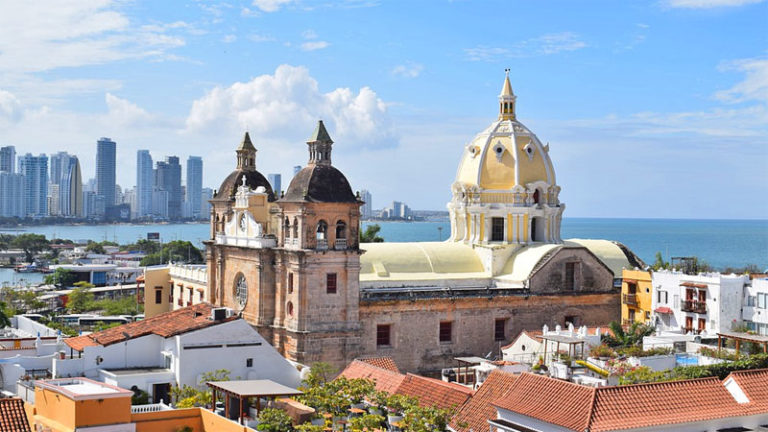 Die historische Kathedrale von Cartagena mit ihrer markanten gelben Kuppel überragt die Altstadt vor der modernen Skyline und dem blauen Meer