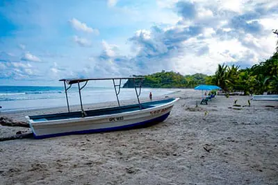 Traumstrand bei Samara auf der Nicoya Halbinsel. Blauer Himmel, im Vordergrund ein Fischerboot.