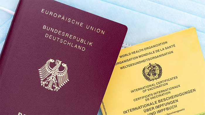 Ein deutscher Reisepass der Europäischen Union liegt neben einem gelben internationalen Impfausweis vor einer Reise nach Südamerika.