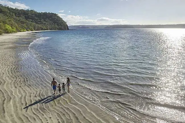 Eine Familie spaziert in einer einsamen Bucht am Strand entlang