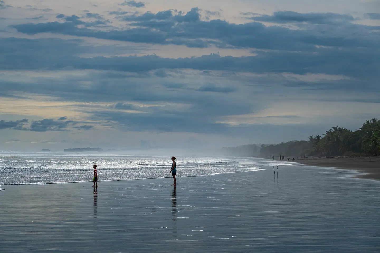 Besucher am Strand von Matapalo, unter einem Himmel mit vereinzelten Wolken.
