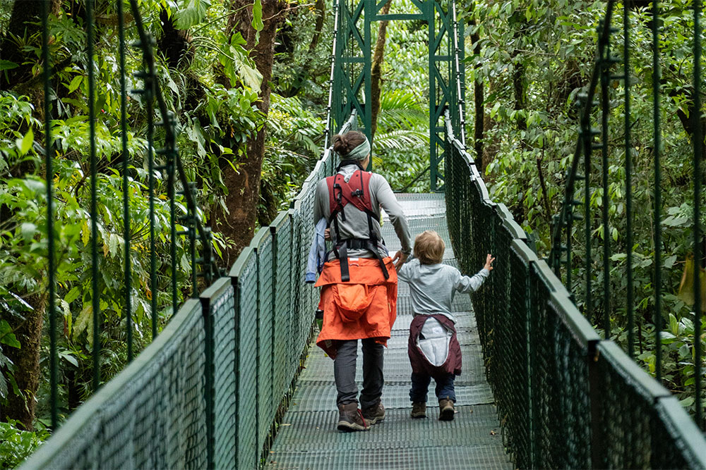 Eine Mutter geht mit ihrem Kind über eine Hängebrücke im Regenwald von Costa Rica