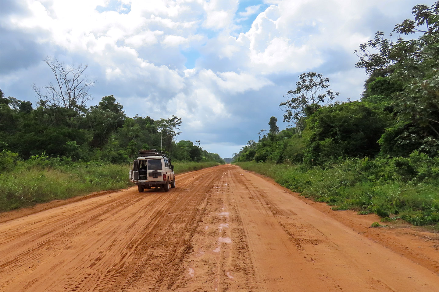 Die Straßen in Suriname sind außerhalb von Paramaribo nicht asphaltiert. Auf dem Bild ist eine langezogene Schotterstraße zu sehen.