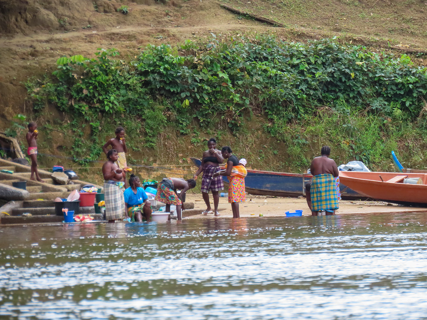 Vom Boot aus gesehen auf dem Upper Suriname River: Eine Gruppe von Frauen und Kindern von den Maroon wäscht am Fluss