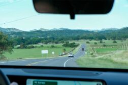 Blick aus dem Auto: eine Landsctraße steckt sich in die weite Landschaft. Am Horizont ruhen sanfte Hügel der Anden.