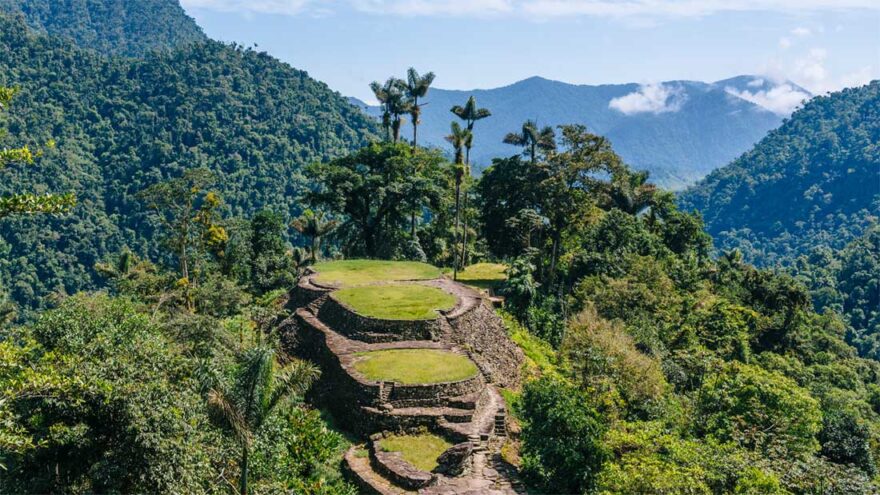 Blauer Himmel. Davor liegt die Ruinenstadt Ciudad Perdida auf einem Hügel, der terrassenförmig aufgebaut ist.